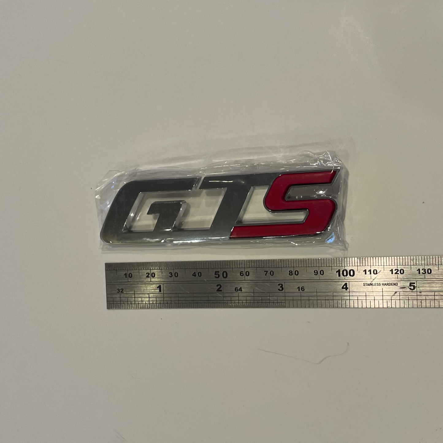 GTS logo decal in packaging with a ruler for scale on a white background