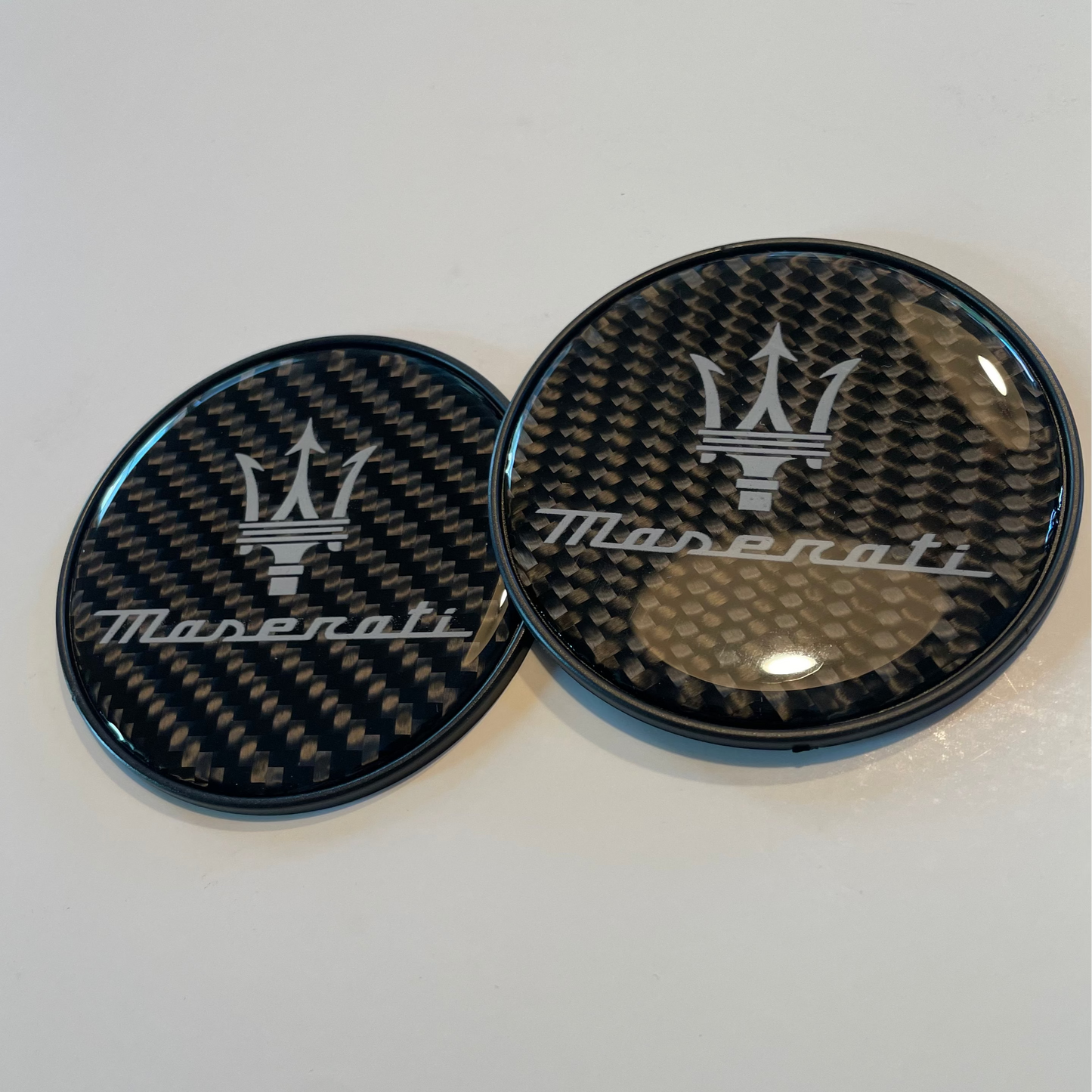 Two Maserati car emblem badges on a white background