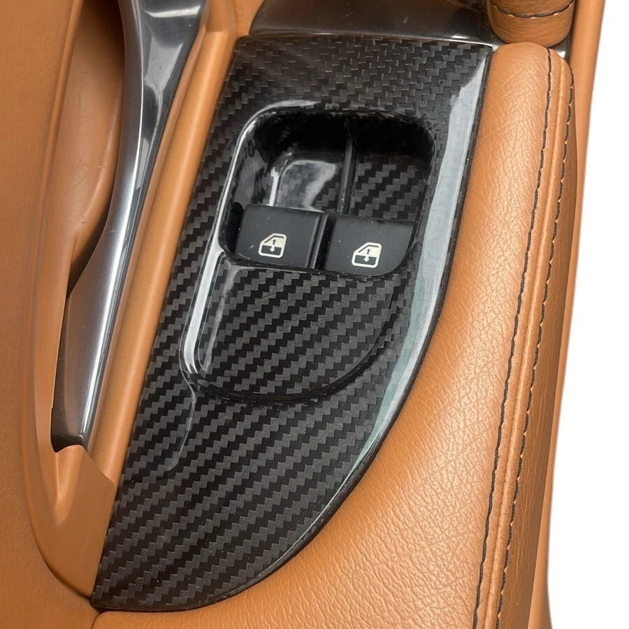 Car interior door panel with carbon fiber texture and buttons on a tan leather background