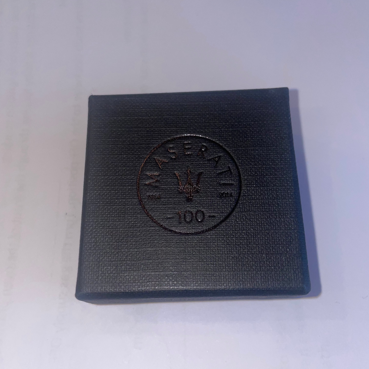 Black square box with embossed logo on a white background