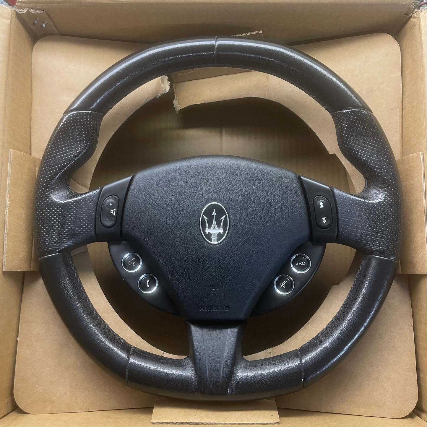 Black steering wheel with Maserati logo in a cardboard box