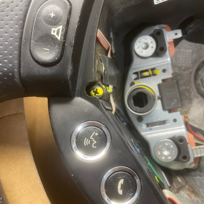 Close-up of a car steering wheel with control buttons and dashboard interior.