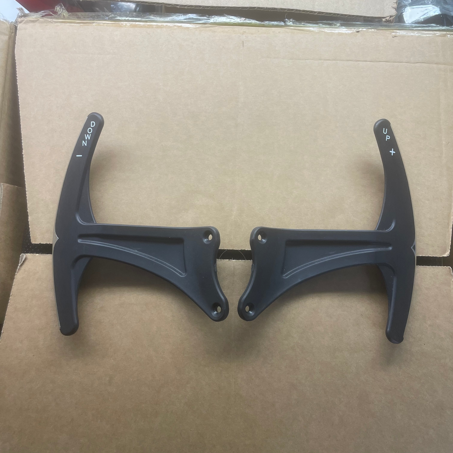 Two black metal brackets on a cardboard surface