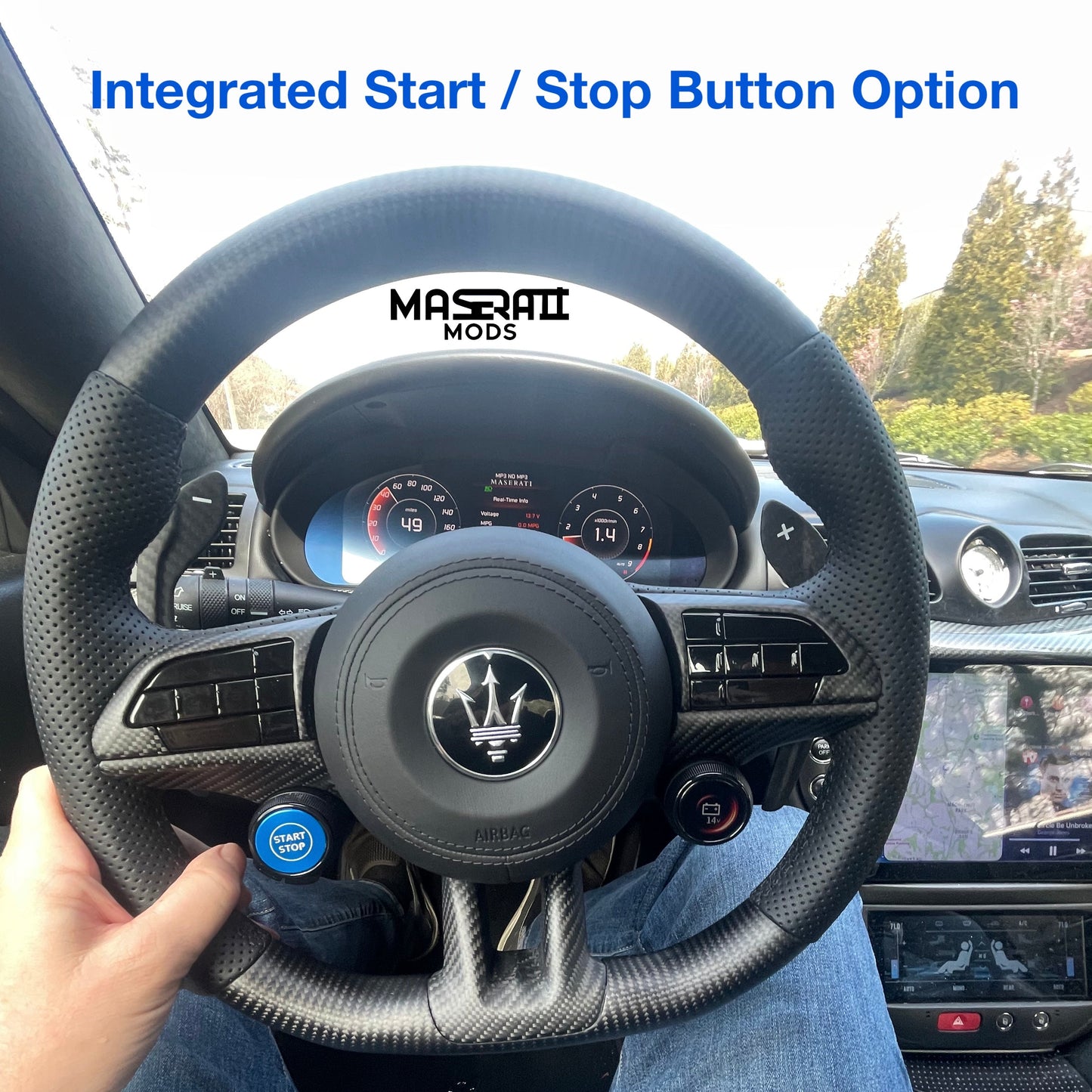 Steering wheel of a Maserati with a hand on the rim, showing the brand logo.