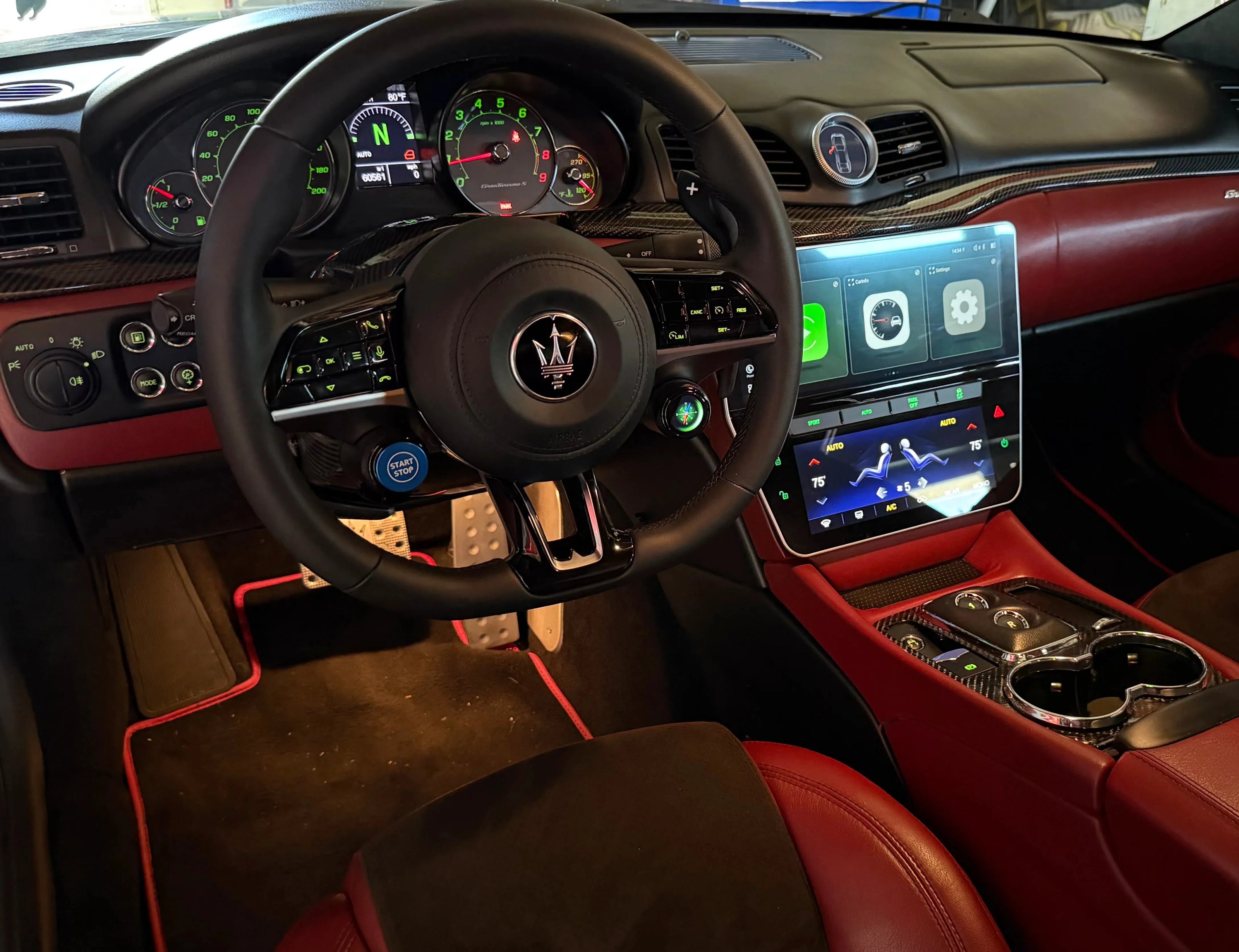 Luxury car interior with red leather seats and Maserati steering wheel.
