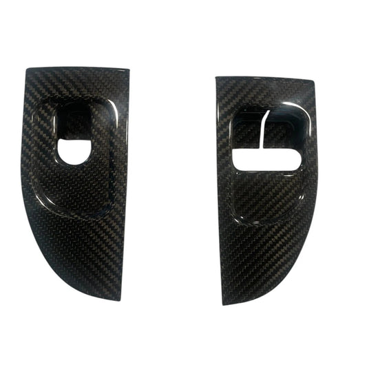 Two carbon fiber car door panels on a white background